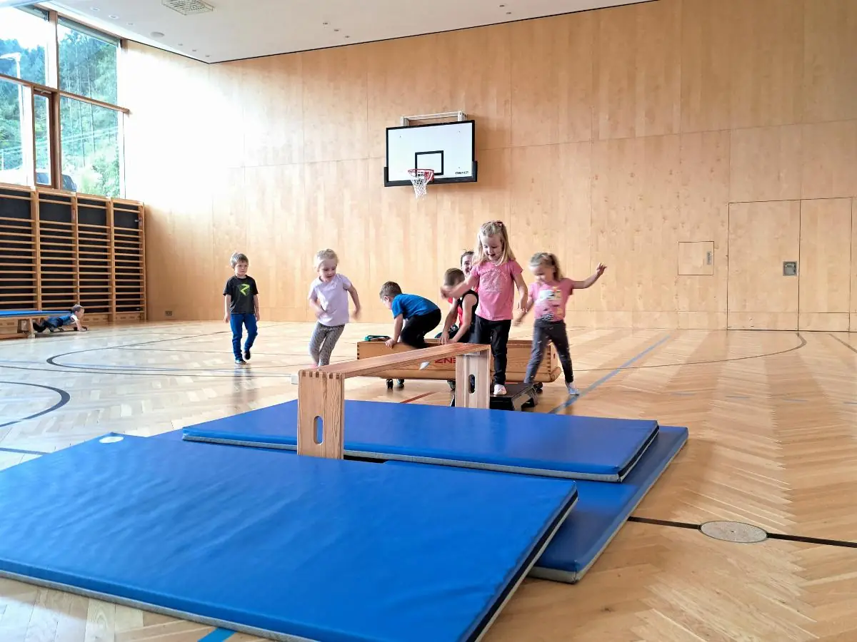 Kinder turnen an den aufgebauten Geräten im Turnsaal.