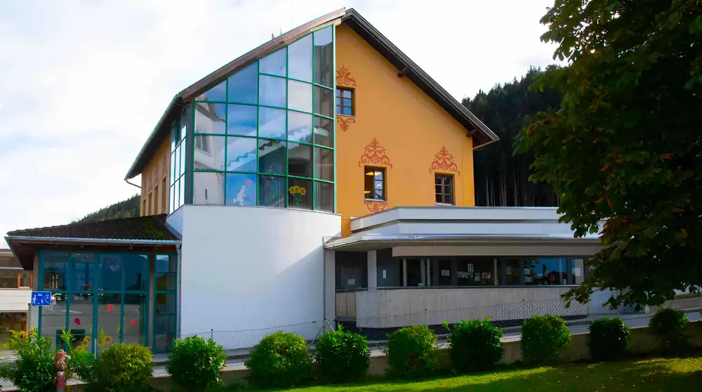 Das Gebäude des Kindergartens Hatting mit Garten und verglastem Giebel.